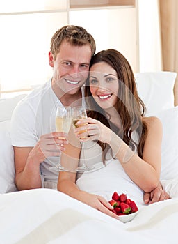 Enamored couple drinking champagne lying in bed photo