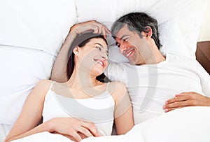 Enamored couple hugging lying in their bed photo