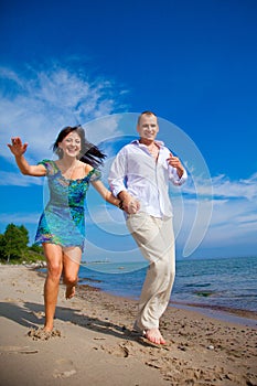 Enamored couple running along the coast of sea