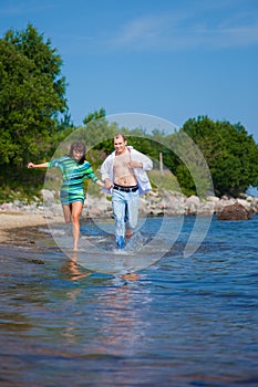 Enamored couple running along the coast of sea