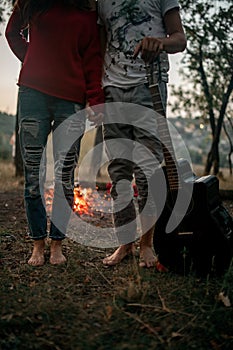 Enamored couple stands with guitar on picnic in forest.