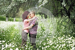 Enamored guy and girl in a green park with white daisies