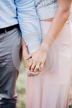 Enamored man and woman stand side by side, woman holds man by the hand, close-up