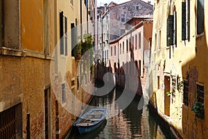 Enchanted canal in the middle of Venice, small boat floats between historic houses in Italy