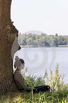 Enchanted Dreams: Young Woman Gazing at the Forest Lake from Beneath a Tree