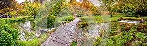 Enchanted eden garden bridge over pond in horizontal panoramic Nymph Garden or Giardino della Ninfa in Lazio - Italy photo