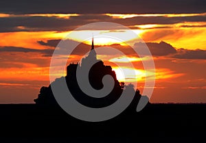 Enchanting sunset with fiery sky with orange and red clouds and Mont Saint Michel abbey