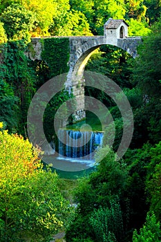 View of Cecco Bridge in Ascoli Piceno with waters of Castellano river flowing below and vegetation photo