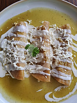 Enchiladas is Mexican cuisine made with rolled or folded corn tortillas and bathed in some spicy sauce with cream and cheese