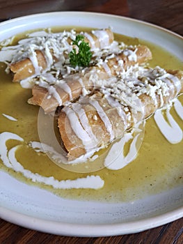 Enchiladas is Mexican cuisine made with rolled or folded corn tortillas and bathed in some spicy sauce with cream and cheese