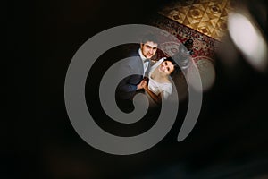 Enclosed top view on beautiful young bride and handsome groom embracing at old stairs with the background of gorgeous