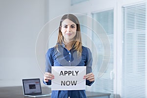Encouraging 'APPLY NOW' sign held by professional