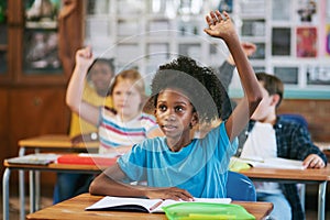 Encouraging engagement. a diverse group of children sitting in their school classroom and raising their hands to answer