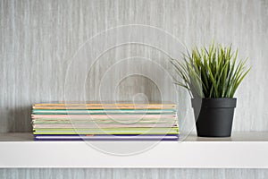 Encyclopedia books on white shelf with plant in a vase