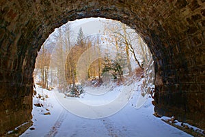End of dark arched empty tunnel with views of mountain landscape in winter