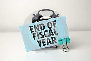 end of fiscal year is written in a blue sticker near a black alarm clock