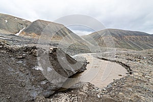 The end of the glacier. A brown river, the meltwater from the Longyear Glacier, coming from under the ice. Longyear