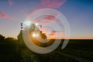 End of a harvest day on a grain field in summer with tractor