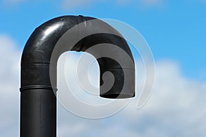 End of industrial shower, U-turn of black plastic pipe on blue sky background