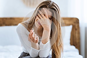 End of marriage concept. Crying woman covers her face with hand and holds wedding ring.