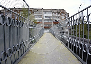 pedestrian bridge over suburban road and curved continuation of wooded recreational trail