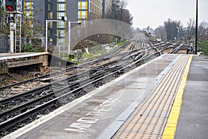 End of platform on train station at London, Mind the step written down, many railway crossings in distance
