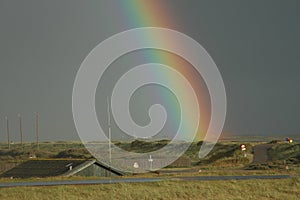 The end of the rainbow. A rainbow seems to hit the ground in the flat land