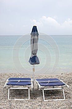 End of summer concept: close sun umbrella and sun beds on a beach with copy space