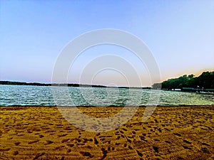 The end of summer empty beach with footprints in the sand at dusk.