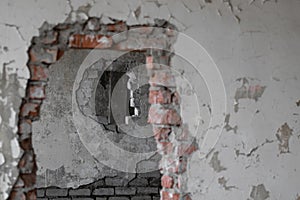 An end-to-end hole in a brick wall inside an old abandoned and ruined industrial building covered with paint in a collapsed