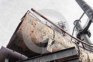 End of very large metal pipe, decaying industrial site