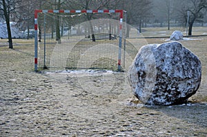 The end of winter on the football field. big balls of snow on the lawn near the soccer goal. rural children built a snowman from t