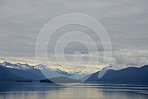 Endicott Arm, Alaska, USA: Snow-capped mountains behind a small island