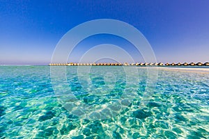 Endless blue sea and blue sky with luxury water villas in Maldives island beach. Wide angle view of