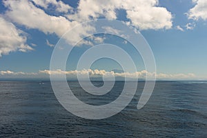 The endless clear blue sea and the blue sky with white clouds merge on the horizon. Seascape. Natural background