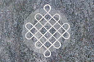 Endless knot engraved on stone surface.