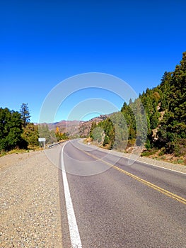 Endless road with curve in mountainous landscape and blue sky. Driving and Landscape concept