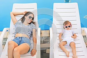 Endless summer. Cute baby and mother relaxing at sunbed