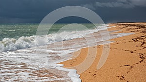 Endless yellow sandy beach with white foam waves