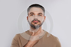 Endocrine system. Man doing thyroid self examination on light grey background