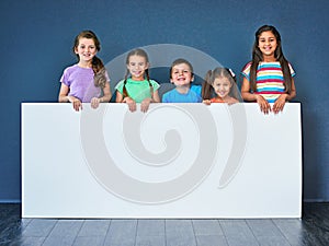 Endorsed by kids for kids. Studio shot of a diverse group of kids standing behind a large blank banner against a blue