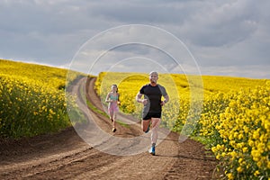 Endurance runners on a dirt track in a canola field, training