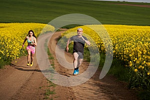 Endurance runners on a dirt track in a canola field, training