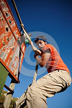 Endure and conquer. a young man climbing over an obstacle at military bootcamp.