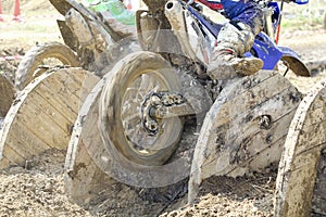 Enduro bikes pass obstacle cable drums in track.