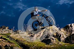 Enduro Cyclist Riding the Bike on the Rock at Night. Extreme Sport Concept. Space for Text.