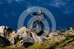 Enduro Cyclist Riding the Bike on the Rock at Night. Extreme Sport Concept. Space for Text.