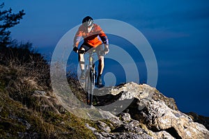 Enduro Cyclist Riding the Bike on the Rock at Night. Extreme Sport Concept. Space for Text.