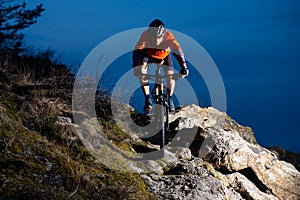 Enduro Cyclist Riding the Bike on the Rock at Night. Extreme Sport Concept. Space for Text.