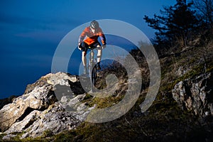 Enduro Cyclist Riding the Bike on the Rock at Night. Extreme Sport Concept. Space for Text.